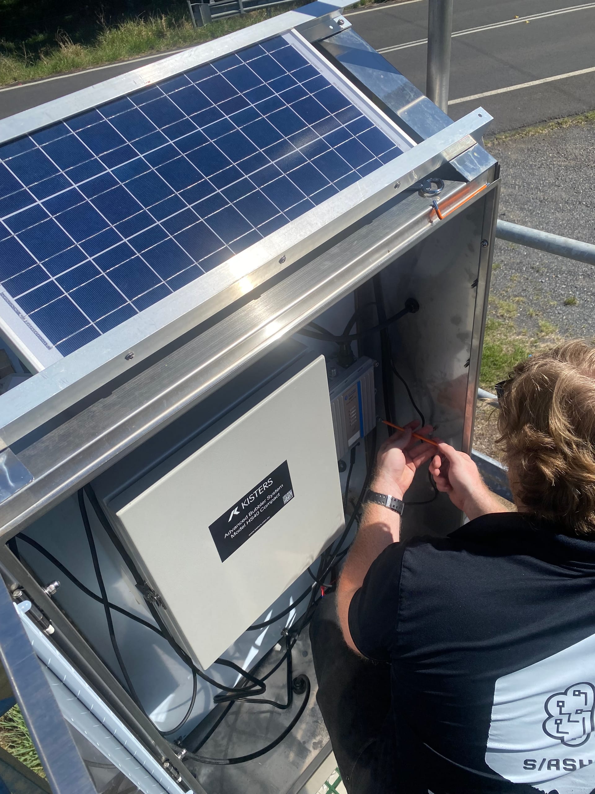 A SlashTech technician connecting wiring inside a solar-powered monitoring enclosure